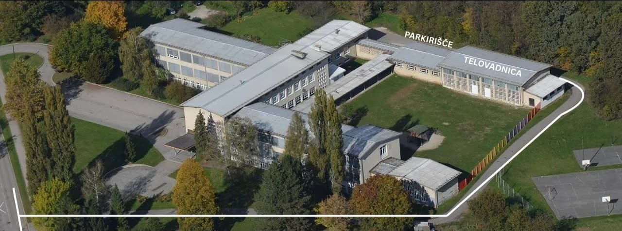 Letalski posnetek šole: parkirišče je za šolo, pot do telovadnice vodi ob igrišču.